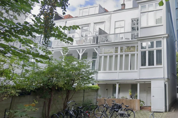 Beschermd en begeleid wonen in rustig hofje in binnenstad van Den Haag met witte gevel en dakterras voor cliënten in herstel van verslaving